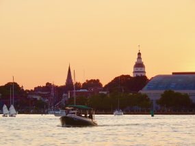 a small boat in a body of water with a city in the background
